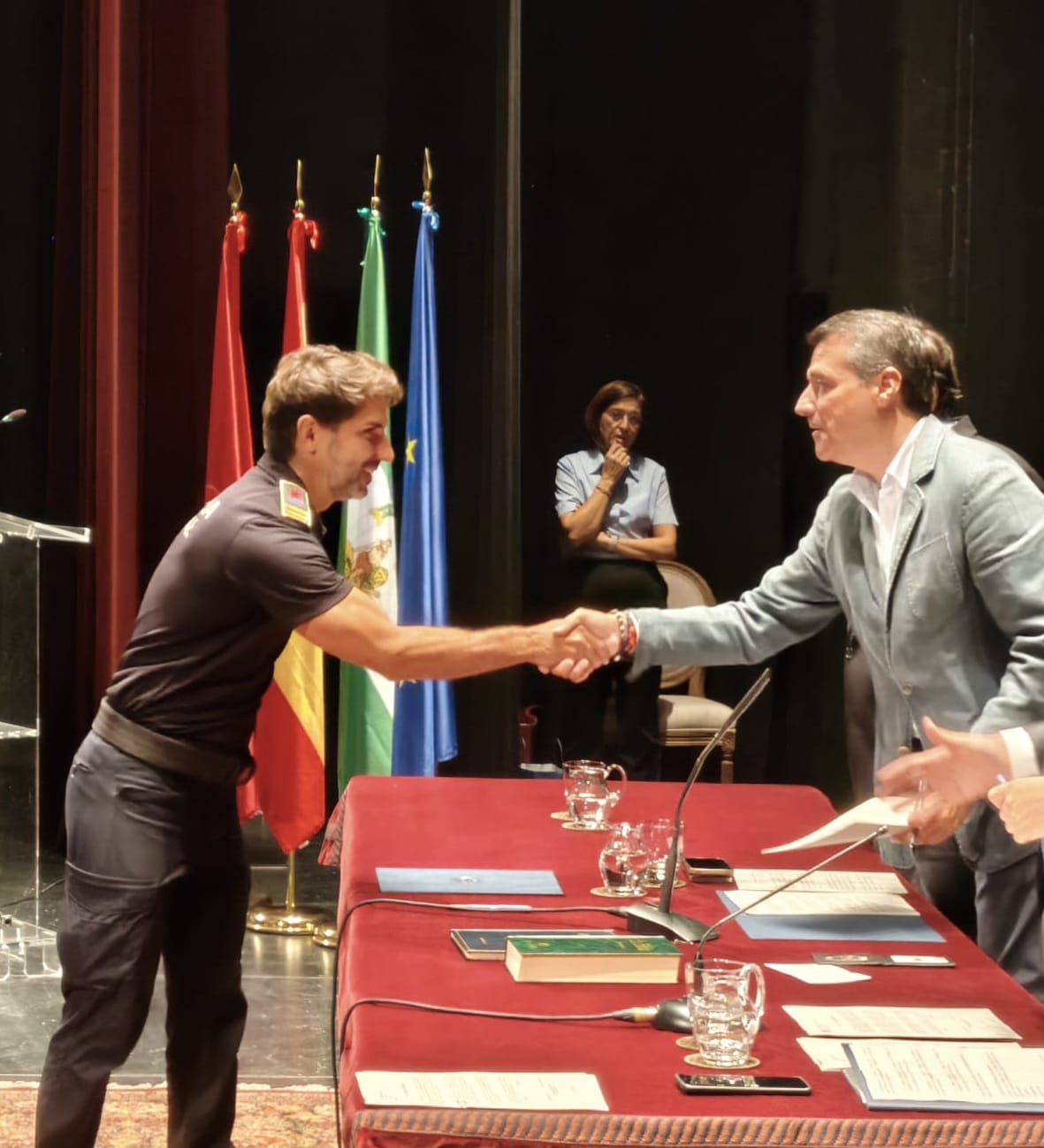Javier Arroyo estrechando la mano en un acto oficial ante las banderas